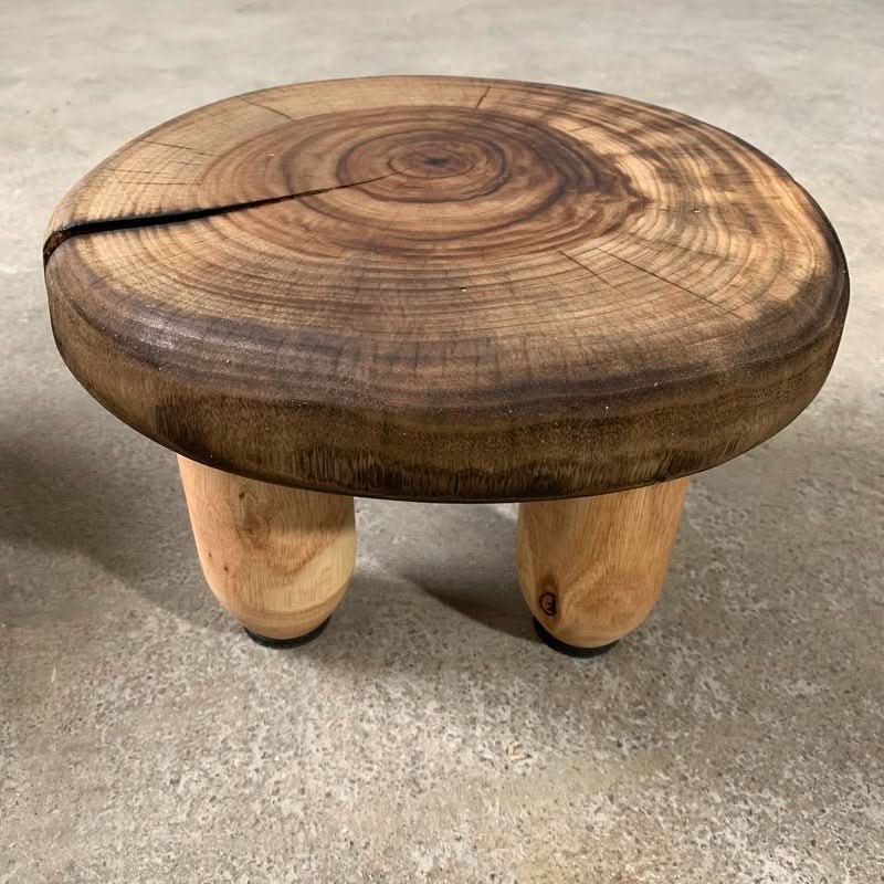 Rustic wood stools with a charred top and natural wood legs, perfect for home decor.